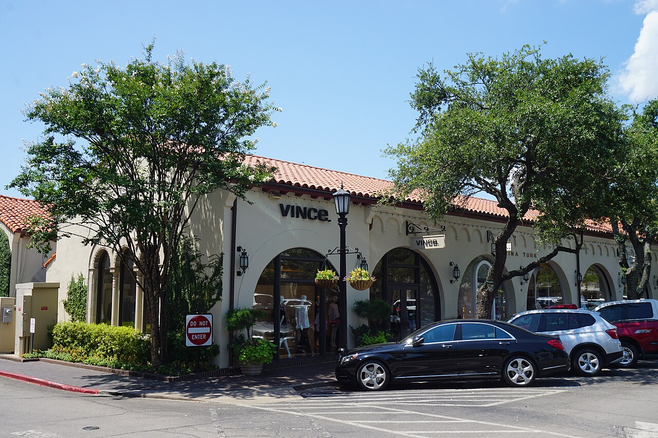 The pale stucco, red tile roof and arched storefronts of Highland Park Village